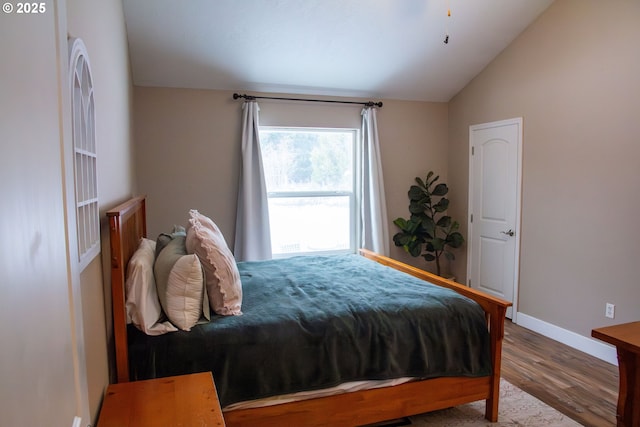 bedroom with lofted ceiling, hardwood / wood-style floors, and white fridge