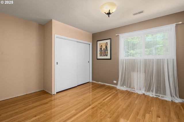 unfurnished bedroom featuring a closet, light wood-type flooring, and visible vents