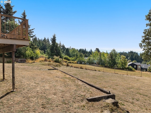 view of yard featuring a deck, a rural view, and fence