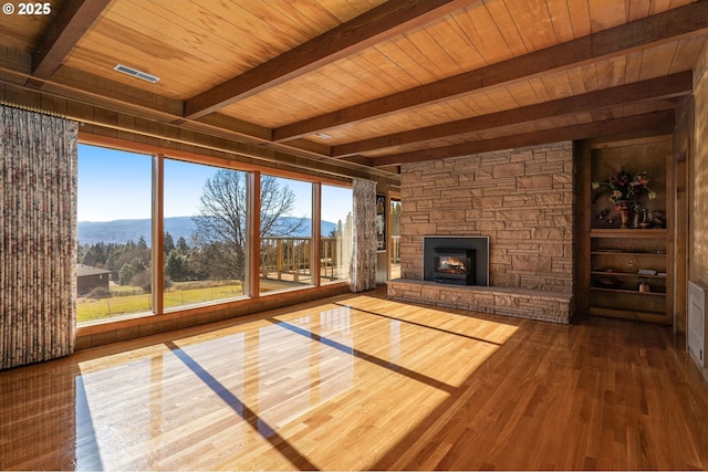 unfurnished living room with a stone fireplace, dark wood-style flooring, beam ceiling, and wood ceiling