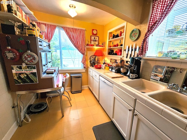 kitchen with tile countertops, white cabinetry, backsplash, light tile patterned floors, and white dishwasher