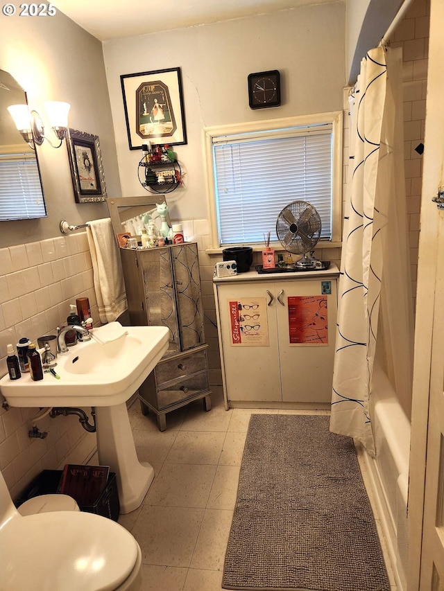 full bathroom with tile patterned floors, toilet, sink, tile walls, and shower / bath combo