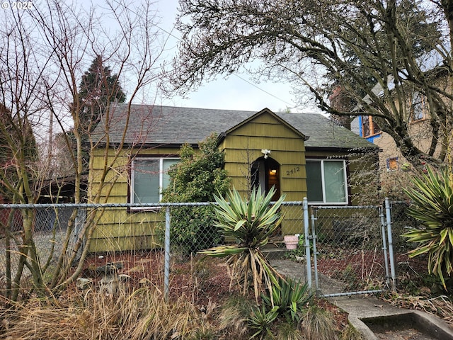 bungalow-style house featuring a fenced front yard, a gate, and a shingled roof