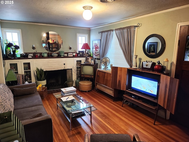 living room with ornamental molding, hardwood / wood-style floors, a textured ceiling, and a wealth of natural light