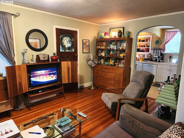 living room with crown molding, wood-type flooring, and a textured ceiling