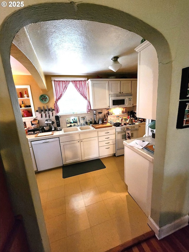 kitchen with white cabinetry, a textured ceiling, and white appliances