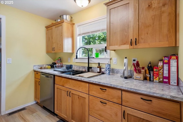 kitchen with a sink, stainless steel dishwasher, light wood finished floors, and light countertops