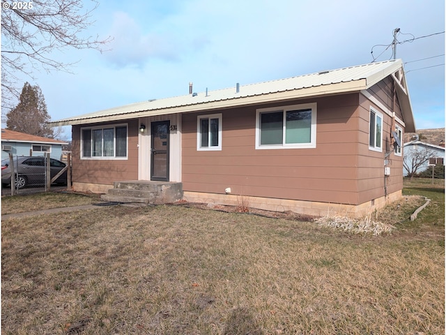 view of front of home featuring metal roof, a front lawn, and fence