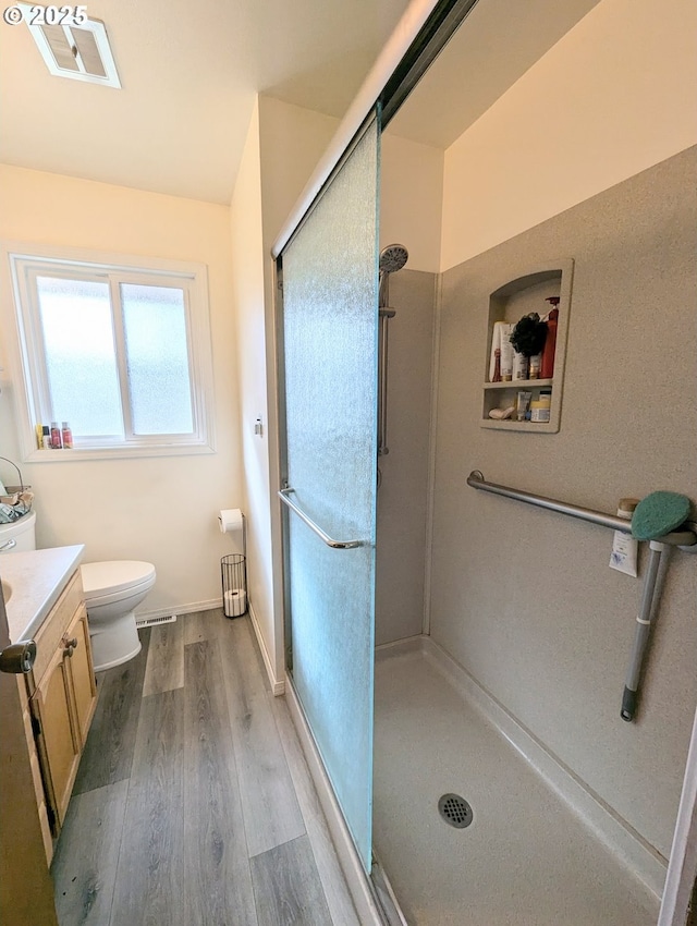 bathroom with visible vents, a shower stall, toilet, wood finished floors, and vanity