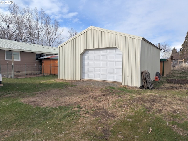 detached garage featuring driveway and fence