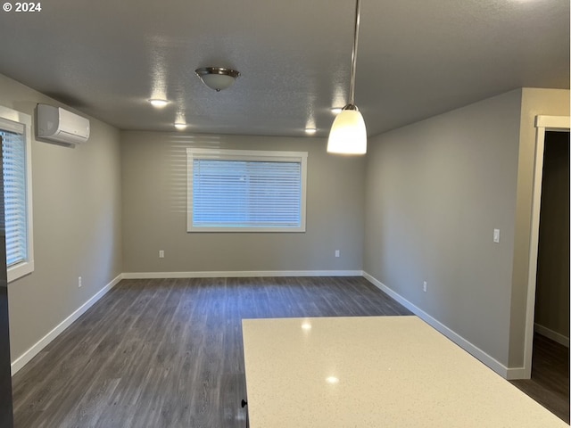 empty room with a wall mounted air conditioner, a textured ceiling, and dark hardwood / wood-style floors