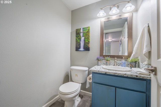 half bath featuring baseboards, wood finished floors, toilet, and vanity