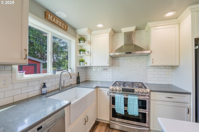 kitchen with open shelves, appliances with stainless steel finishes, a sink, wall chimney exhaust hood, and backsplash