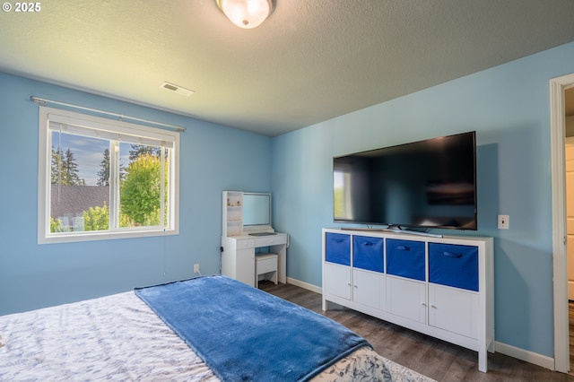 bedroom featuring a textured ceiling, baseboards, wood finished floors, and visible vents