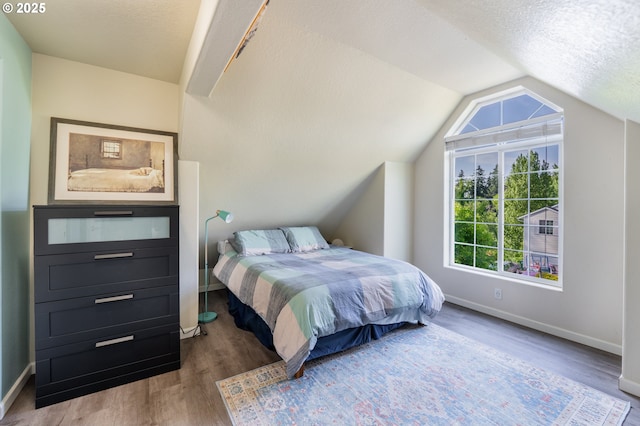 bedroom featuring baseboards, a textured ceiling, wood finished floors, and vaulted ceiling