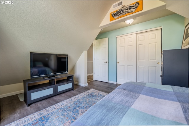 bedroom featuring baseboards, visible vents, wood finished floors, and a closet