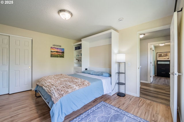 bedroom with a closet, baseboards, and wood finished floors
