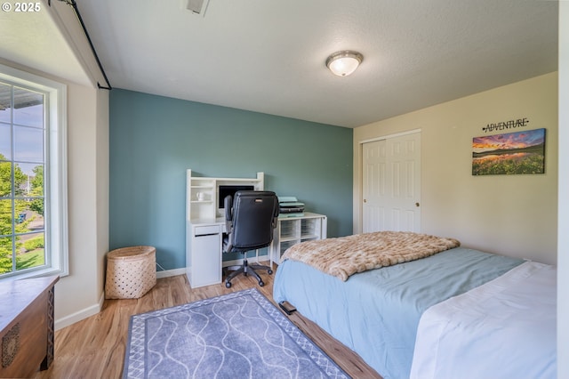 bedroom with baseboards, light wood finished floors, and visible vents