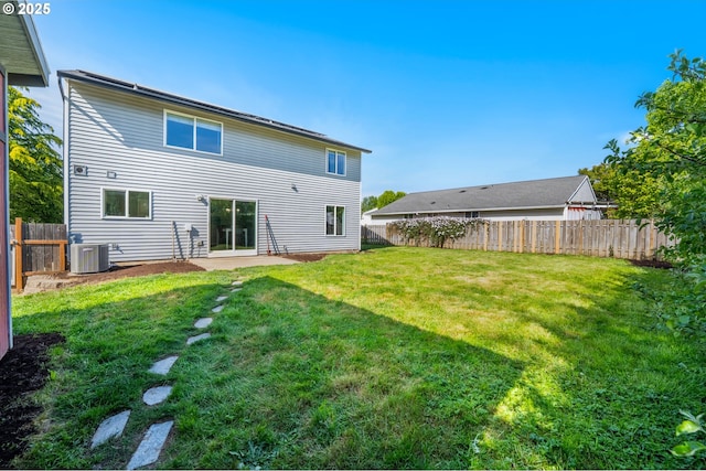 rear view of house with a lawn, central AC unit, and a fenced backyard