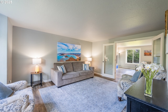 living room with baseboards, a textured ceiling, and wood finished floors
