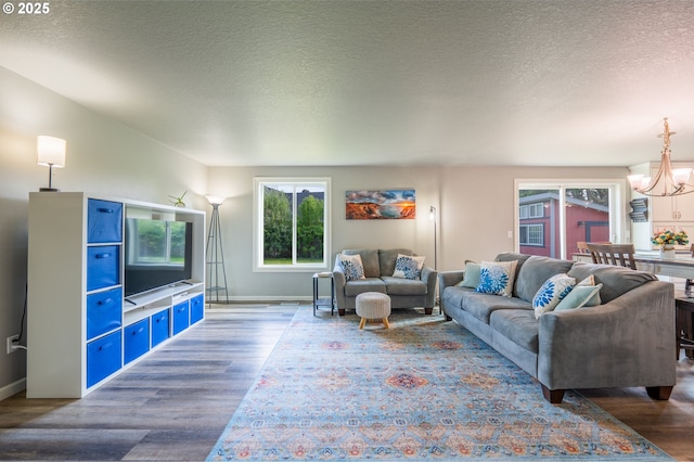 living room featuring a textured ceiling, baseboards, a notable chandelier, and wood finished floors