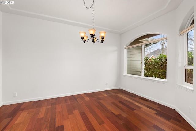 spare room featuring dark hardwood / wood-style floors and a chandelier