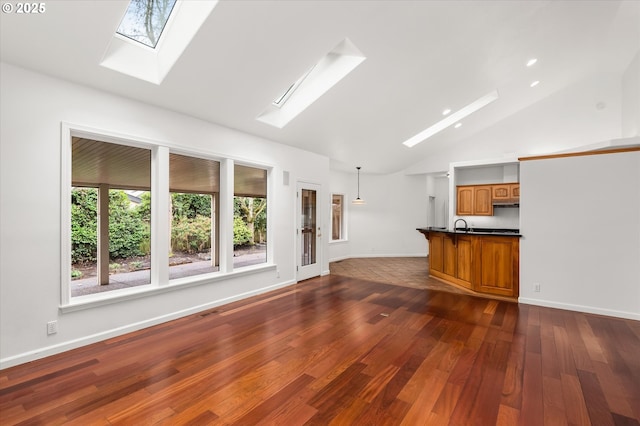 unfurnished living room with dark wood-type flooring, sink, high vaulted ceiling, and a skylight