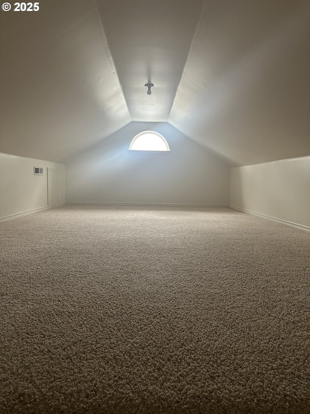 bonus room with lofted ceiling and carpet flooring