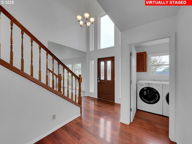 foyer with a chandelier, stairway, a towering ceiling, wood finished floors, and separate washer and dryer