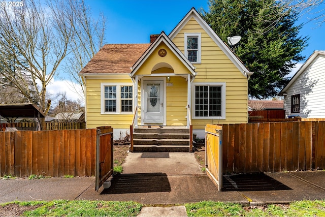 view of front of property with a gate, a fenced front yard, a chimney, and entry steps