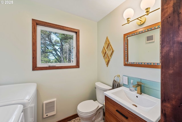 255 Coast Guard Hill Rd, Port Orford, OR 97465 - bathroom with vanity, washer and clothes dryer, toilet, visible vents, and heating unit