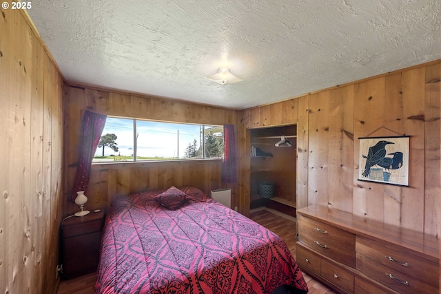 255 Coast Guard Hill Rd, Port Orford, OR 97465 - bedroom featuring a textured ceiling, wood walls, and wood finished floors