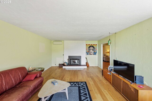 255 Coast Guard Hill Rd, Port Orford, OR 97465 - living room featuring a fireplace, a textured ceiling, an AC wall unit, and light wood-type flooring