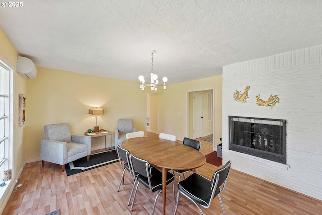 255 Coast Guard Hill Rd, Port Orford, OR 97465 - dining space with a wall unit AC, a brick fireplace, a textured ceiling, light wood-style floors, and an inviting chandelier