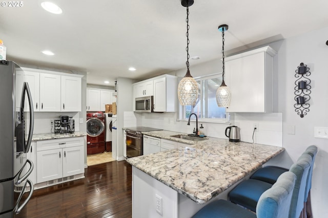 3490 Midway Ave NE, Salem, OR 97301 - kitchen featuring stainless steel appliances, washer and dryer, a peninsula, a sink, and dark wood-style floors