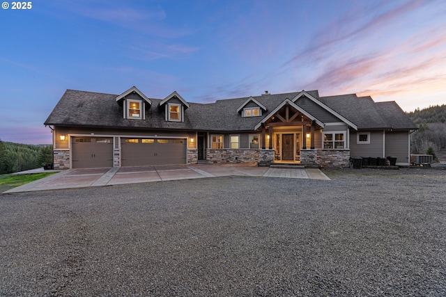 craftsman-style house with driveway, stone siding, and cooling unit