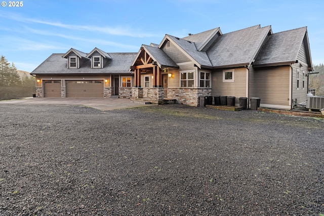 craftsman inspired home with a garage, stone siding, driveway, and central air condition unit