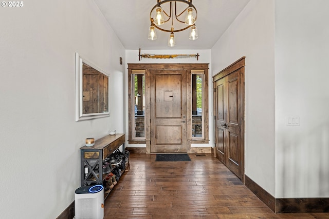 entrance foyer featuring baseboards, dark wood finished floors, and a notable chandelier