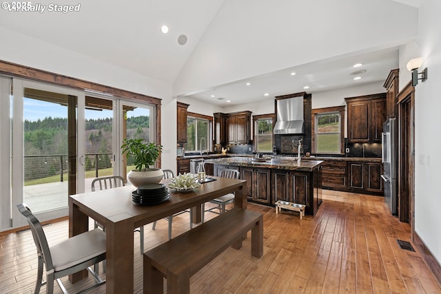 dining area featuring plenty of natural light, high vaulted ceiling, light wood-type flooring, and visible vents