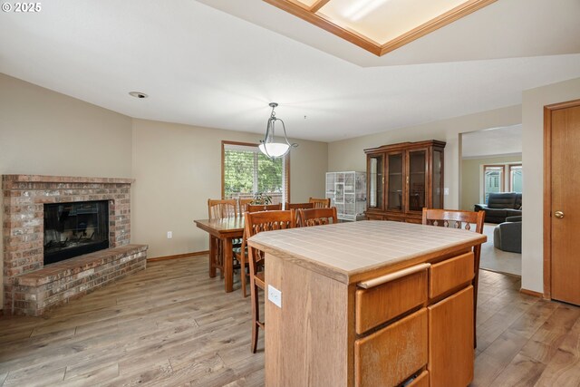 12705 NE 101st St, Vancouver, WA 98682 - kitchen featuring tile counters, light wood-style flooring, a kitchen bar, a brick fireplace, and hanging light fixtures