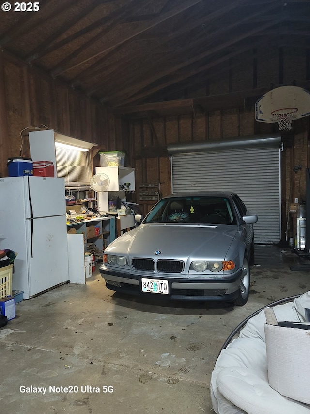 garage featuring white refrigerator and wood walls