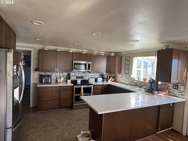 kitchen featuring sink, crown molding, appliances with stainless steel finishes, dark brown cabinets, and kitchen peninsula