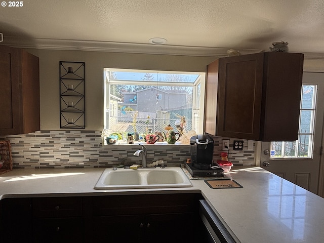 kitchen with dark brown cabinetry, sink, crown molding, and a textured ceiling