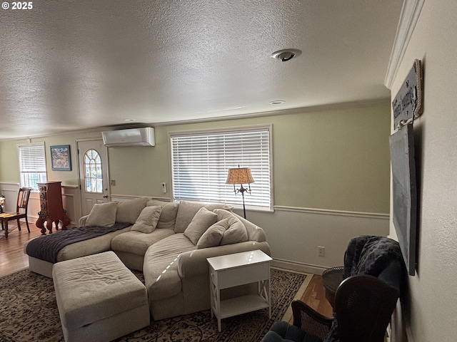 living room featuring wood-type flooring, a textured ceiling, and a wall unit AC