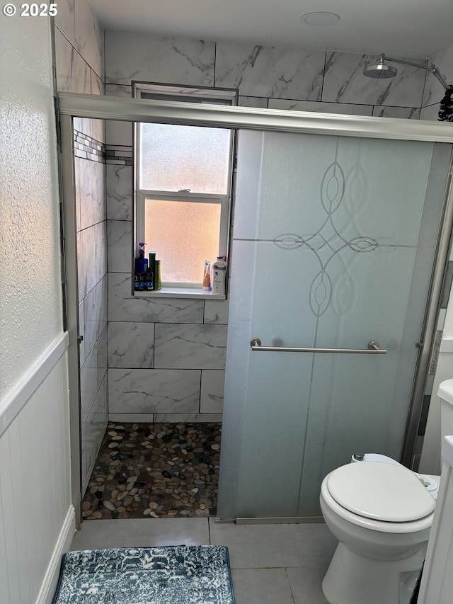 bathroom with toilet, tile patterned flooring, and a shower with door