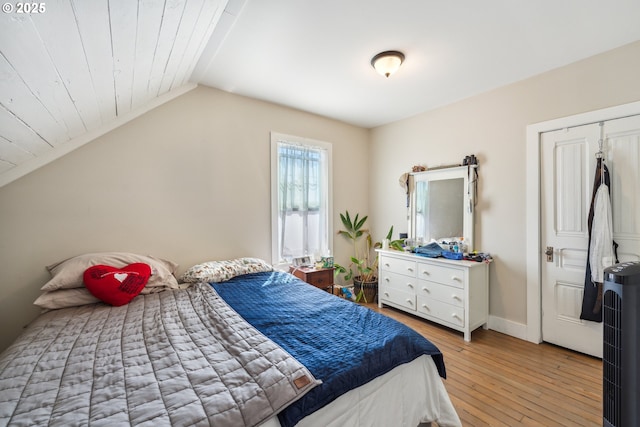 bedroom featuring light wood-style floors, baseboards, and lofted ceiling