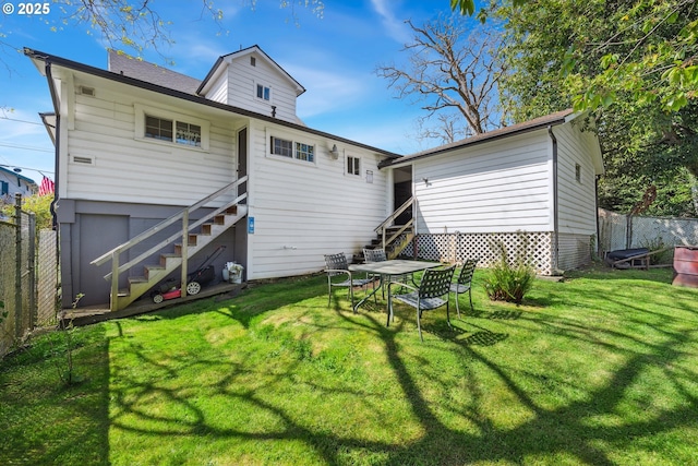 back of house featuring fence, stairs, and a lawn