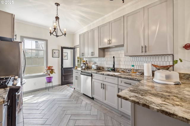 kitchen featuring appliances with stainless steel finishes, a sink, a chandelier, tasteful backsplash, and ornamental molding