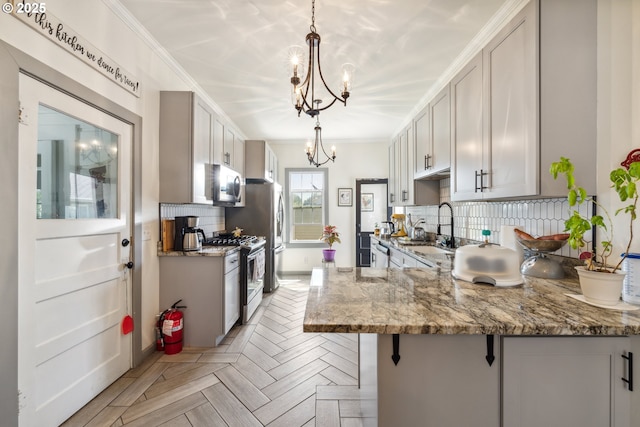 kitchen featuring backsplash, light stone countertops, a sink, a chandelier, and stainless steel appliances