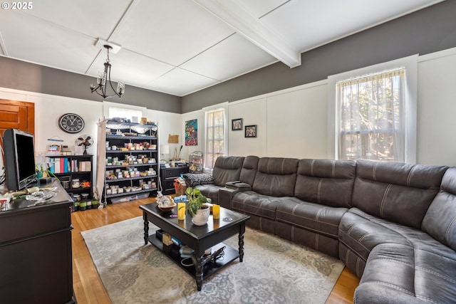 living room with an inviting chandelier, beamed ceiling, and wood finished floors